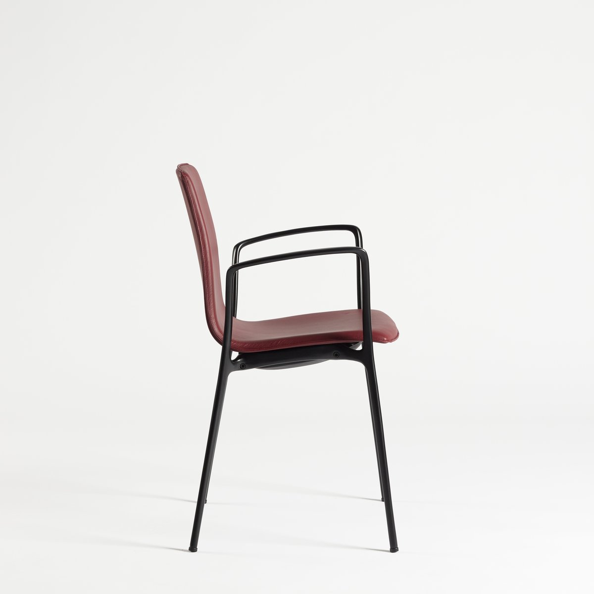 Chaise de réunion Gorka tapissée rouge avec accoudoirs, vue de profil