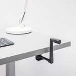 Détail de la manivelle rétractable noire fixée sous le plateau gris dun bureau bench Ogi Drive Bench