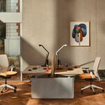 Bureau bench assis-debout Ogi Drive à piètement en feutre gris clair et plateaux en chêne dans un bureau lumineux