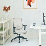 Chaise de bureau à dossier résille beige et assise beige, avec accoudoirs, devant un bureau blanc