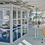 Cabine de réunion vitrée à structure gris clair dans un open space lumineux