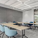 Tables de formation Easy à plateau chêne clair et piétement noir disposées en U dans une salle de réunion