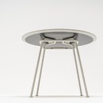 Dessous de la table ronde New School gris clair : tubes courbés de la structure fixés sous le plateau