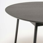 Vue rapprochée du plateau rond chêne noir de la table Unit et de ses pieds en tube Ø 35 mm