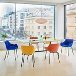 Fauteuils de réunion bleus, jaunes et orange sur pieds noirs autour dune table claire
