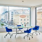 Chaises de réunion bleues pivotantes à roulettes sur étoile noire autour d'une table claire