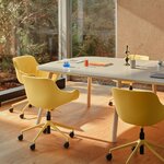 Chaises réglables jaunes à coussin drapé et roulettes autour d'une table de réunion blanche