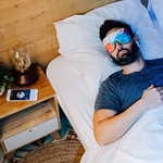 Homme Au Lit Avec Masque connecté HYPNOS de Dreaminzzz Couleur Fantaisie A Côté dUne Lampe et De Son Smartphone