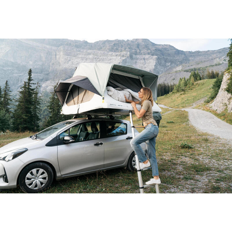 Tente de toit Quechua MH500 ouverte sur une citadine, femme montant à l'échelle, en montagne