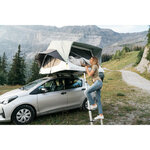 Tente de toit Quechua MH500 ouverte sur une citadine, femme montant à l'échelle, en montagne