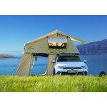 Tente de toit Adventure Xperience 140 ouverte avec son auvent sur une citadine, au bord d’un lac