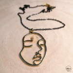 Collier noir et doré avec pendentif visage minimaliste bois