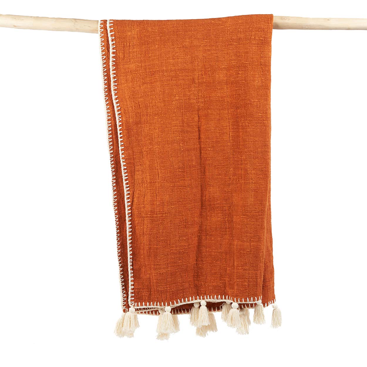Couverture terracotta ou orange avec des broderies beiges, posée sur un support en bois