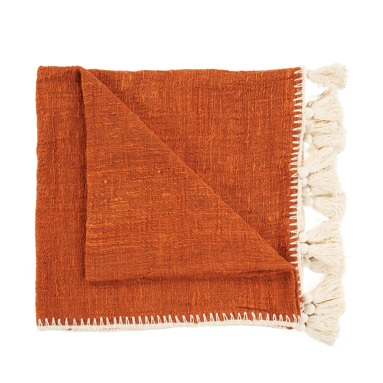 Couverture de lit pliée orange et beige avec pompons