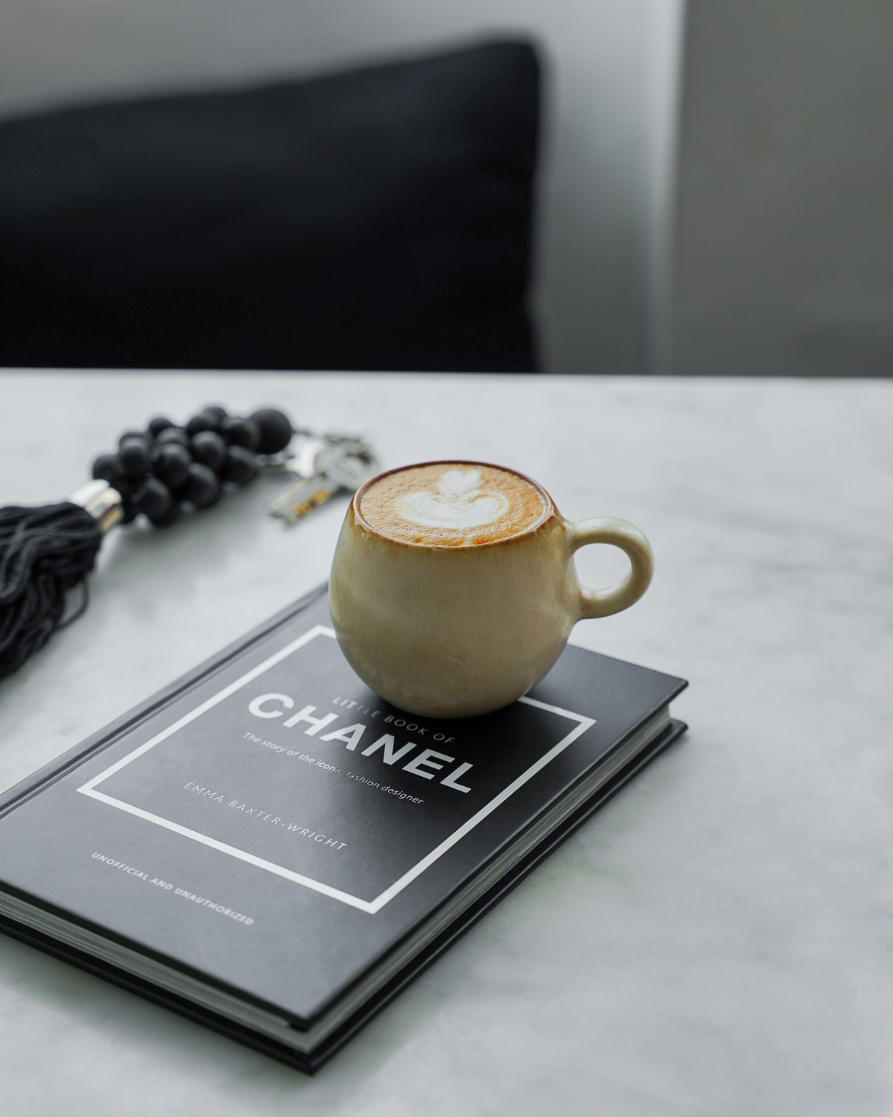 Petite tasse ronde espresso cascais sur livre dans une cuisine avec porte clé noir
