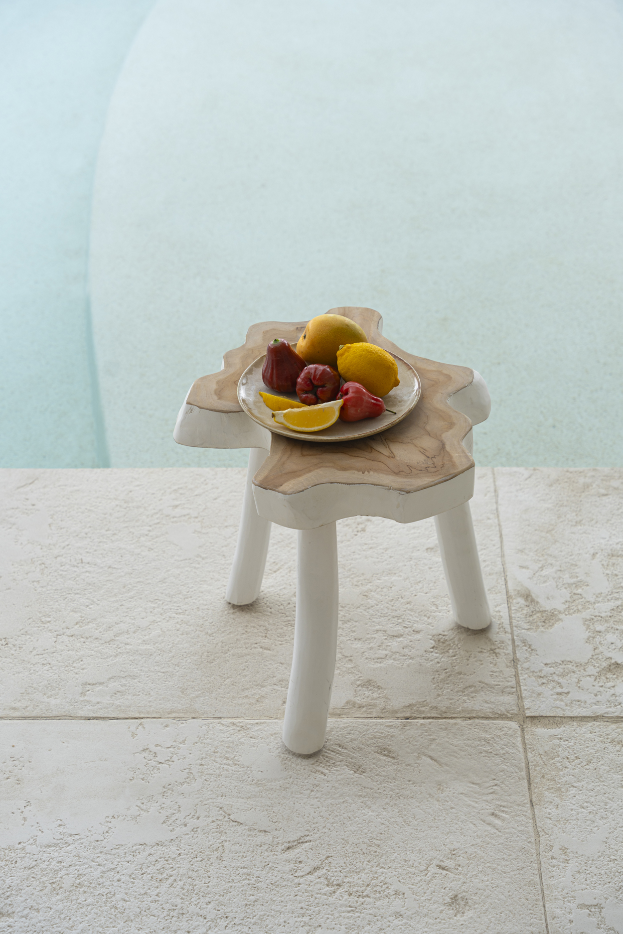 Table dappoint teck et blanc avec assiette céramique cascais beige et fruits au bord de la piscine
