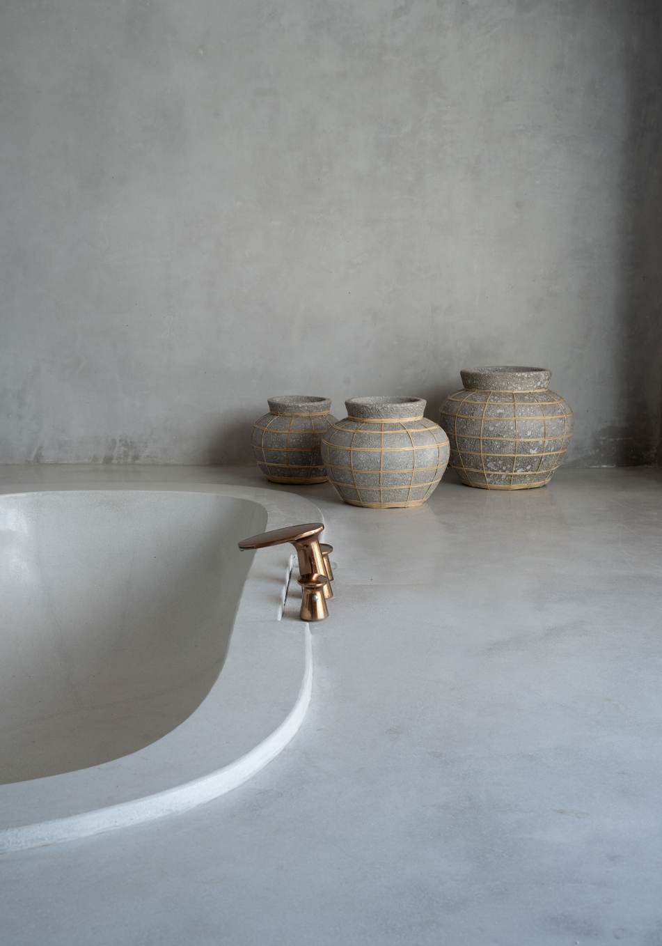 Trio de vases en terre cuite couleur béton et raphia dans une salle de bain