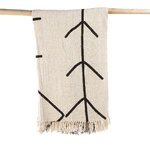 Jeté de lit beige dessins lignes formant des flèches noires et suspendu sur une branche