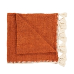 Couverture de lit pliée orange et beige avec pompons