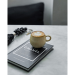 Petite tasse ronde espresso cascais sur livre dans une cuisine avec porte clé noir