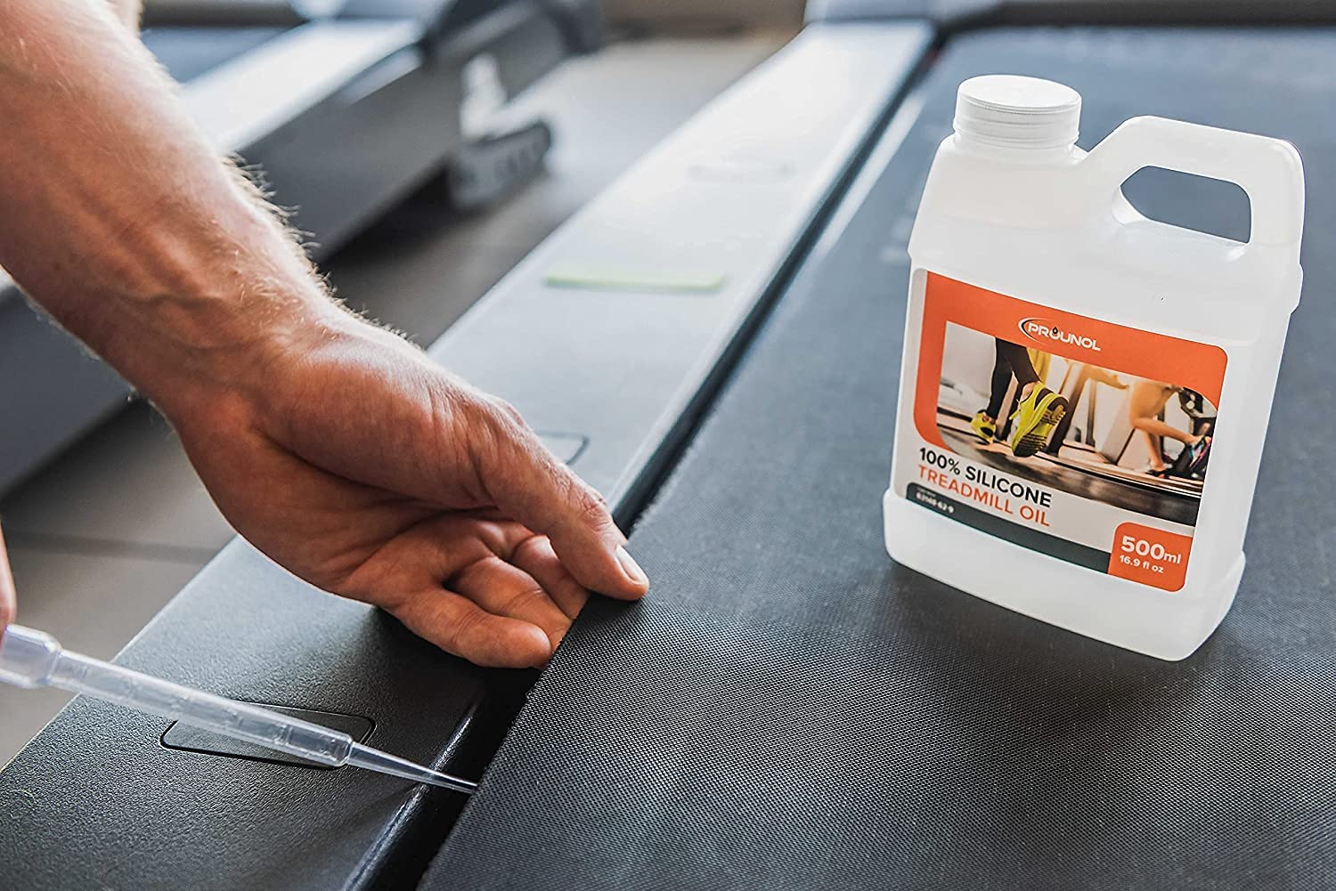 Description: Gérez produits - A person using a bottle of cleaner on a treadmill.