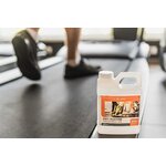 A bottle of tread cleaner, a product used for maintaining and cleaning treadmills, sitting on a treadmill.