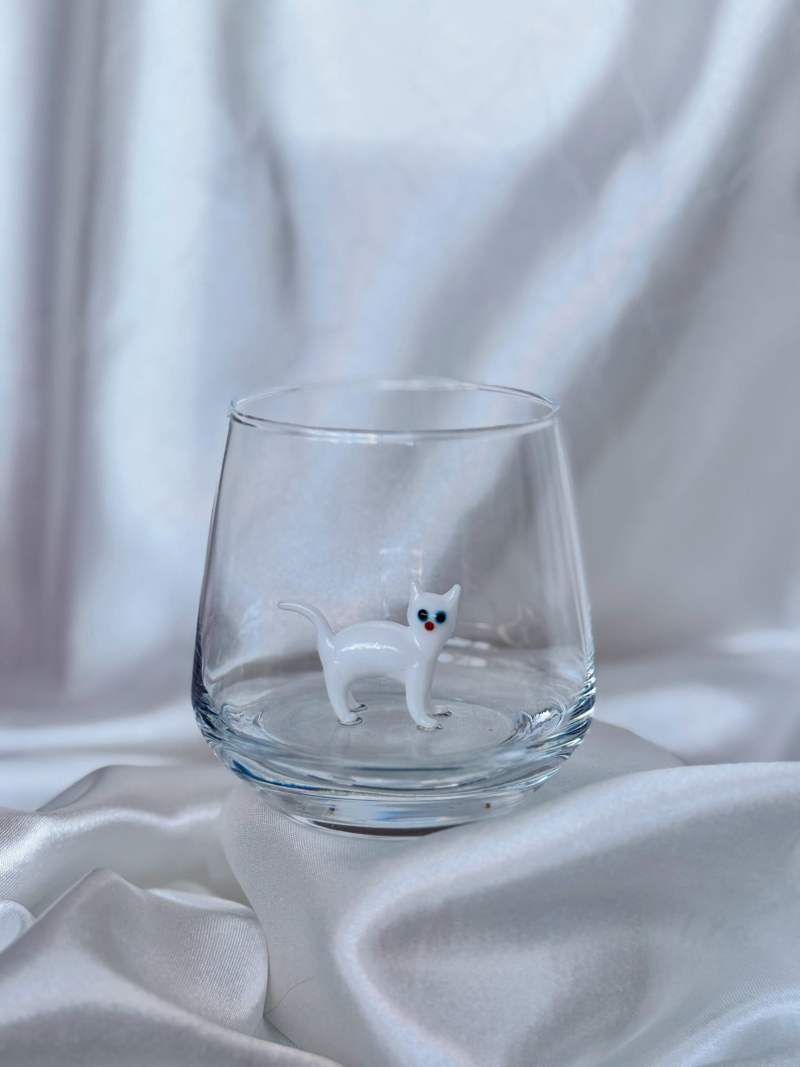 Two Murano cat glasses side by side with different colored kitties inside