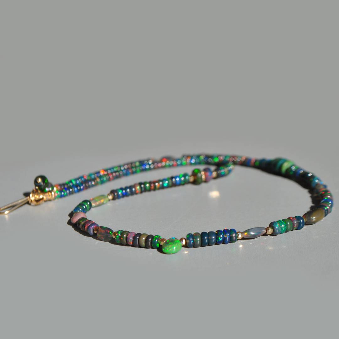 Rondelles dopale noire aux reflets bleus, verts et rouges autour de la goutte centrale du collier