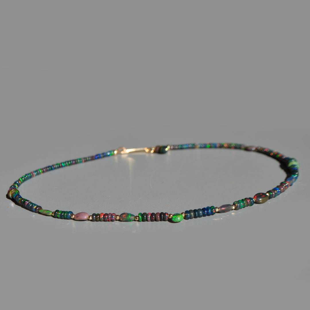 Collier opale noire dÉthiopie posé à plat, goutte dopale verte au centre et perles Gold Filled 14K