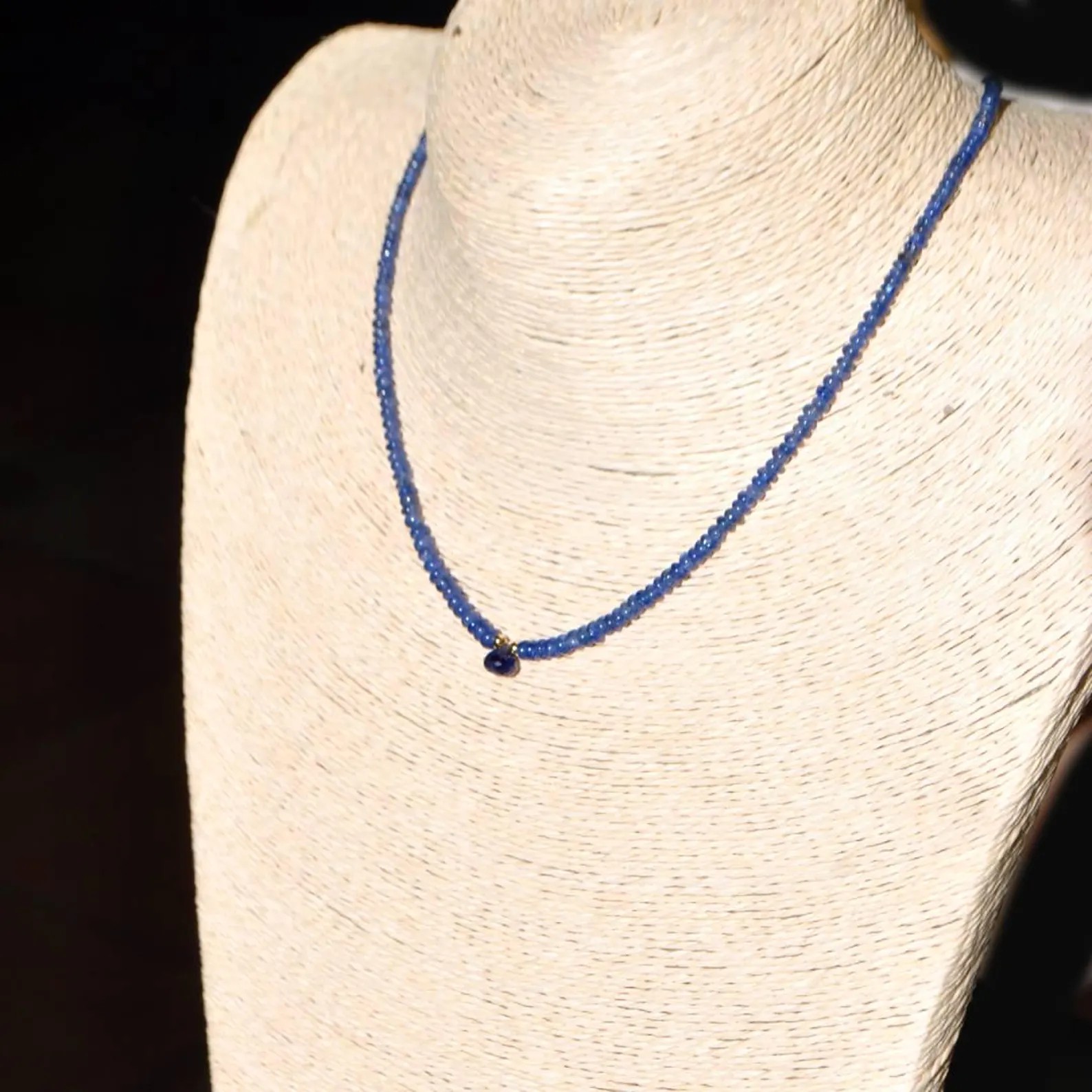 Collier saphir bleu porté sur buste, goutte centrale à la base du cou