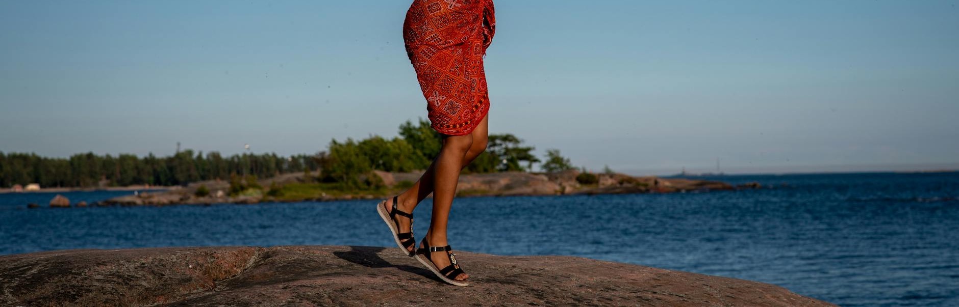 une femme danse avec energie sur une plage rocheuse d helsinki vetue d une tenue coloree