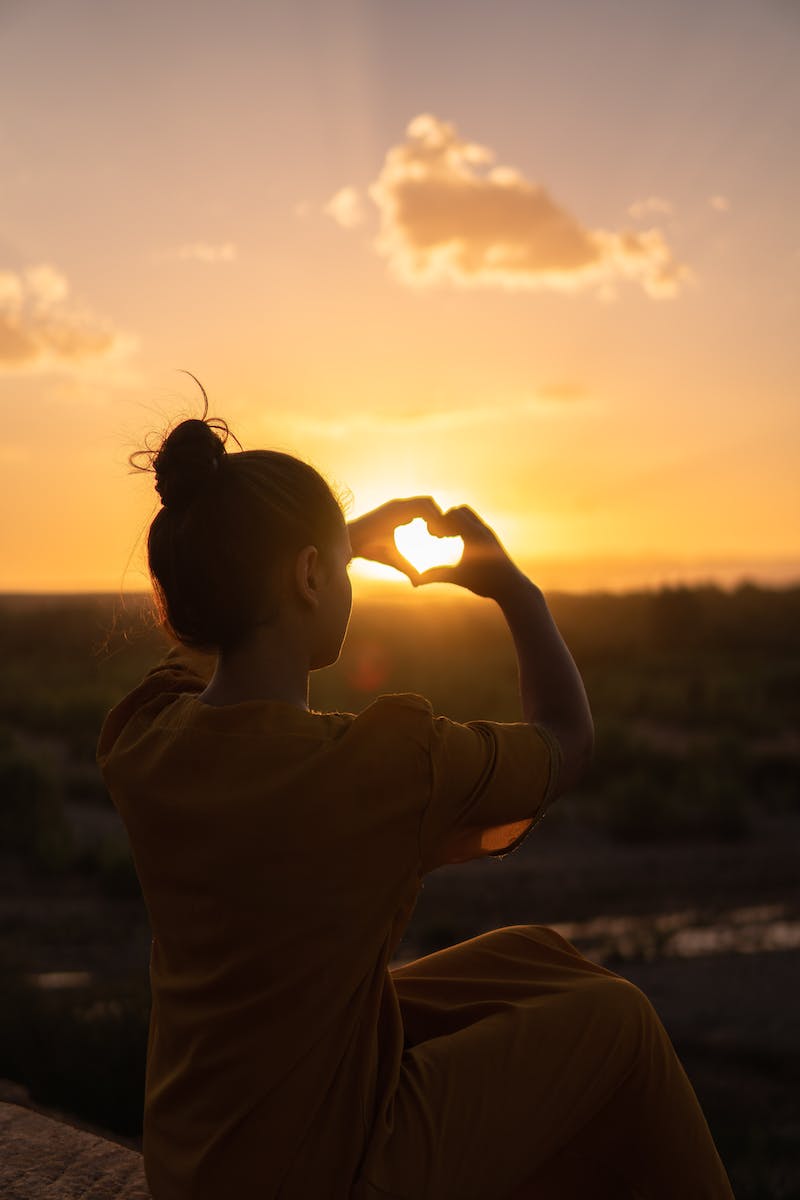 femme assise tout en montrant les mains de signe de coeur