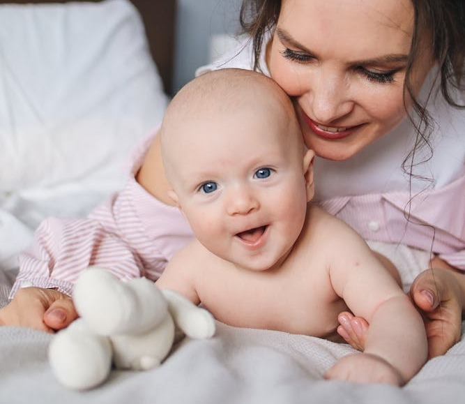 Un bébé avec un doudou et maman