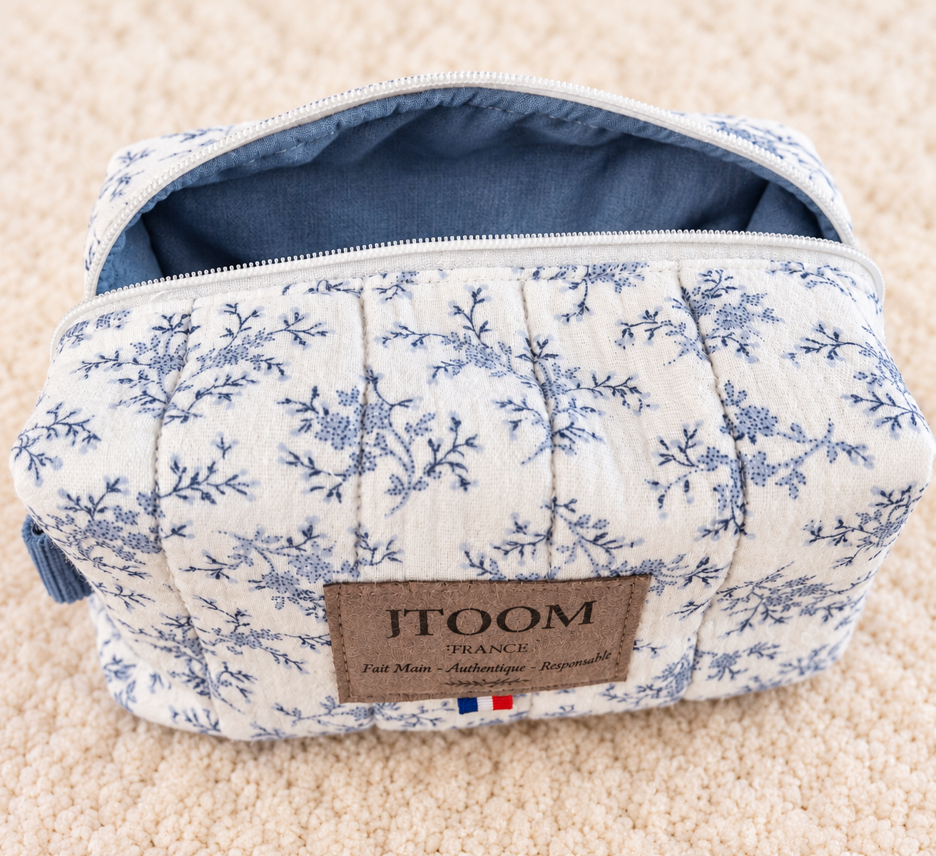Trousse florale bleu poudré sur tapis crème
