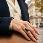 Bague Cléo portée à la main, béton irisé bleu-vert et large anneau en acier doré