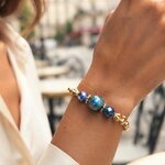 Bracelet Cristal Bleu, perle en béton irisé bleu-vert entre deux perles en verre facetté, sur chaîne dorée