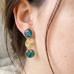 Boucle doreille Râ portée, soleil doré entre deux pastilles de béton bleu irisé