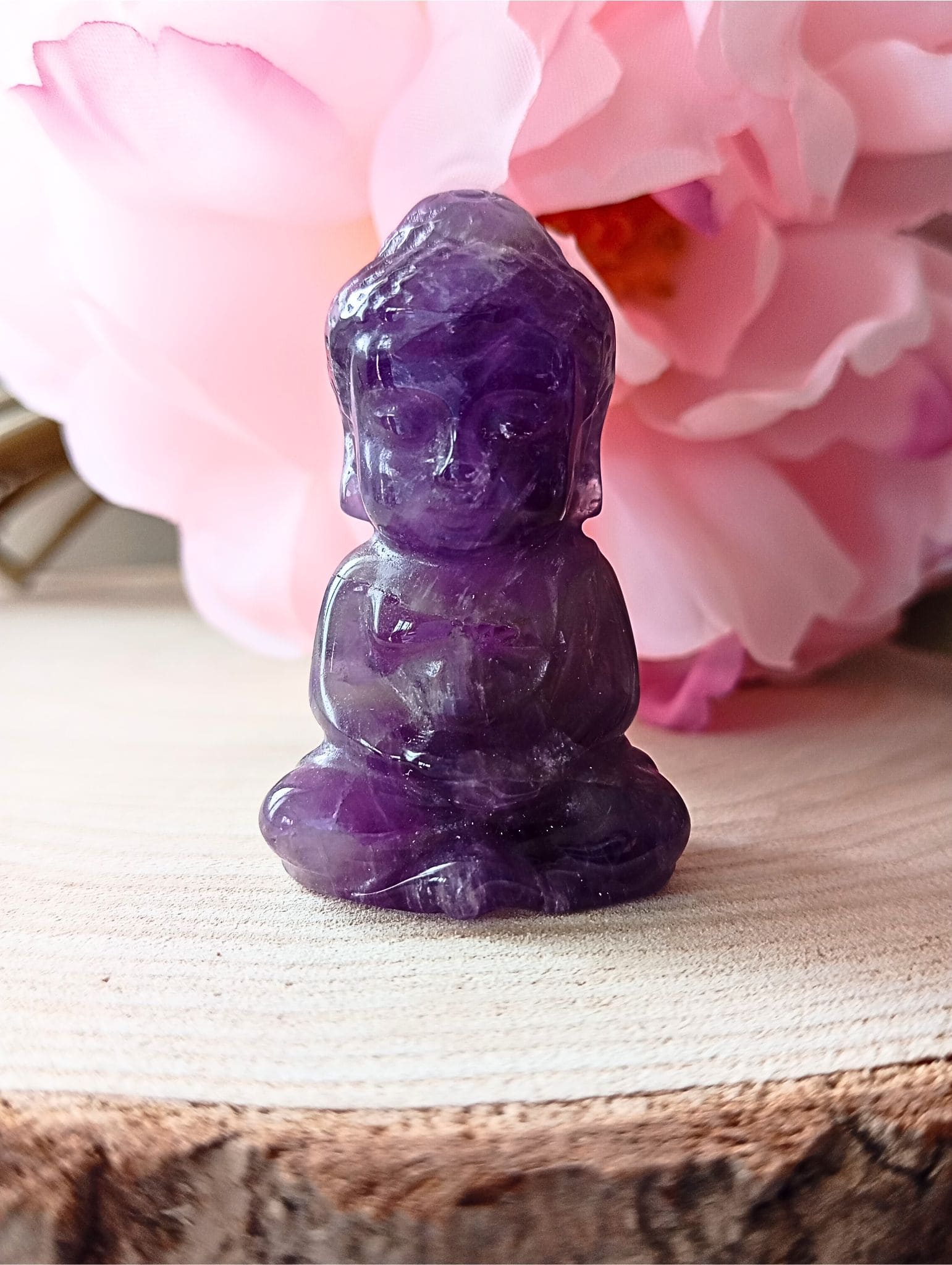 bouddha en améthyste sur rondin de bois