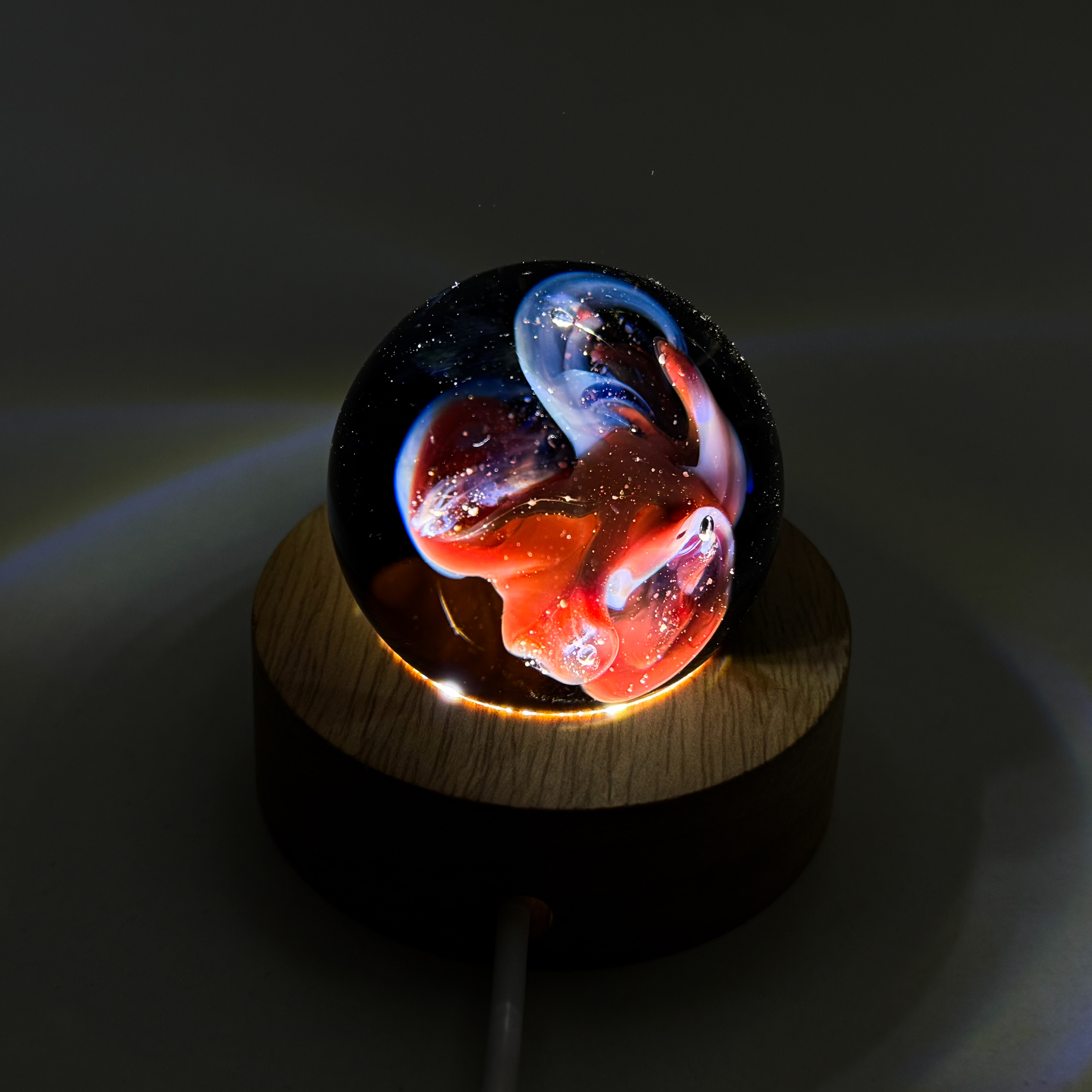 Sphère de verre nébuleuse artisanale sur socle lumineux