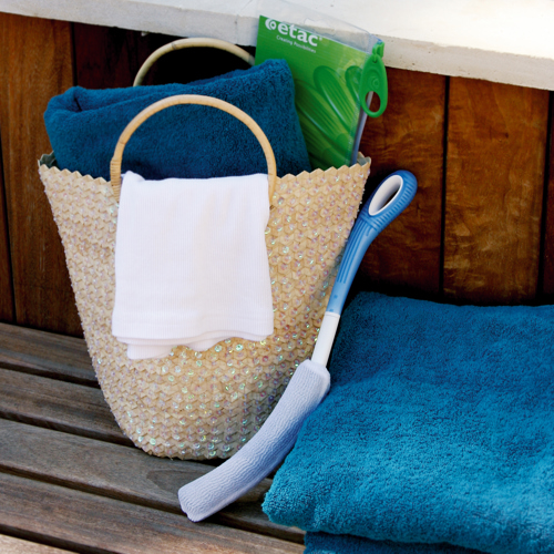 une-brosse-pour-le-corps-cylindrique-avec-manche-long-posee-a-cote-panier-en-osier-et-serviette-bleue-sur-banc-de-sauna