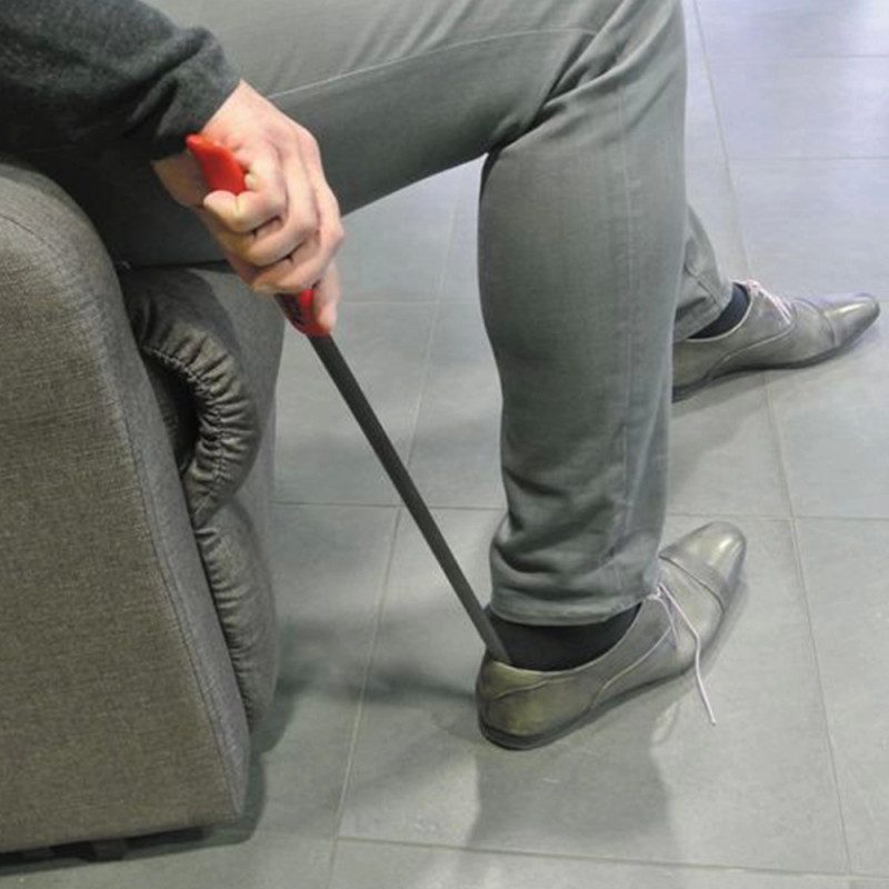 un-homme-assis-enfile-chaussure-grace-chausse-pied-long-en-metal-et-poignee-rouge