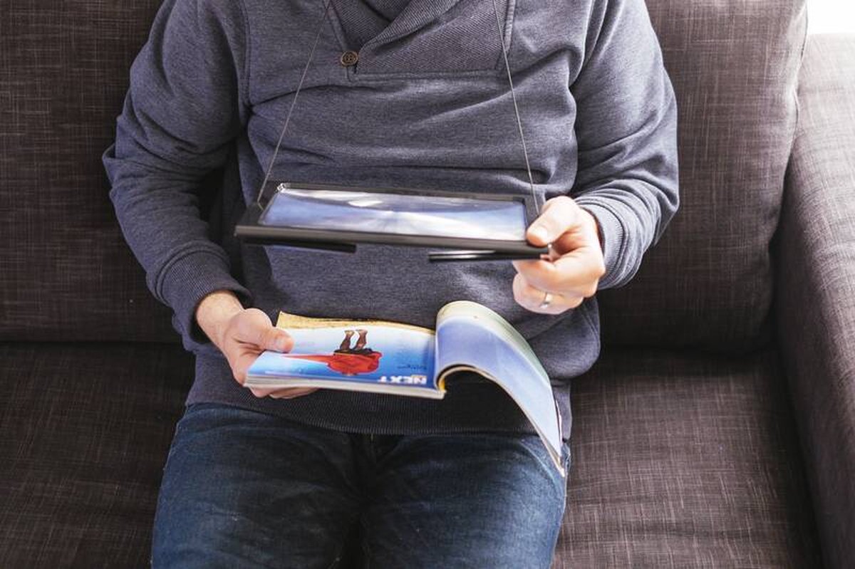 une-personne-lit-un-magazine-en-tenant-une-loupe-grande-taille-suspendue-a-son-cou