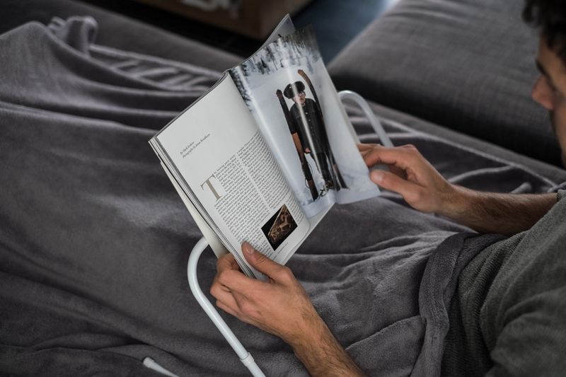 une-personne-lit-dans-un-lit-un-magazine-pose-sur-un-support-de-lecture