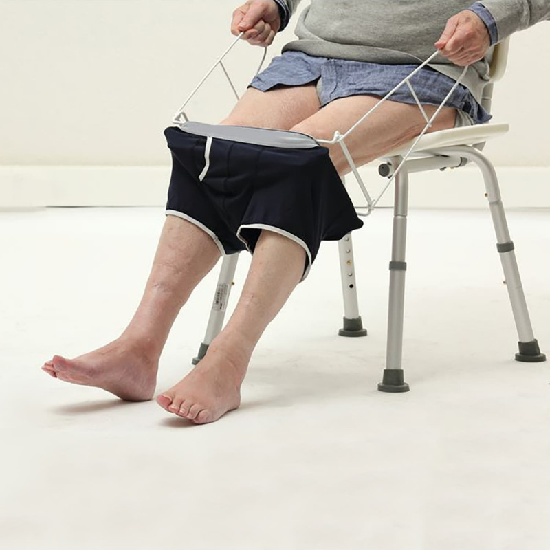 un-homme-assis-sur-une-chaise-enfile-son-slip-avec-enfile-slip-pliable