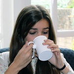 une-femme-boit-avec-une-tasse-anti-renversement-handsteady-dans-son-salon