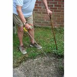 un-homme-jardine-debout-en-s-appuyant-sur-une-canne-de-l-autre-main-il-utilise-une-griffe-de-jardin-a-long-manche