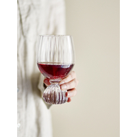 Verre à vin artisanal soufflé bouche, rempli de vin rouge. Mise en situation pour une ambiance de table chaleureuse et élégante.