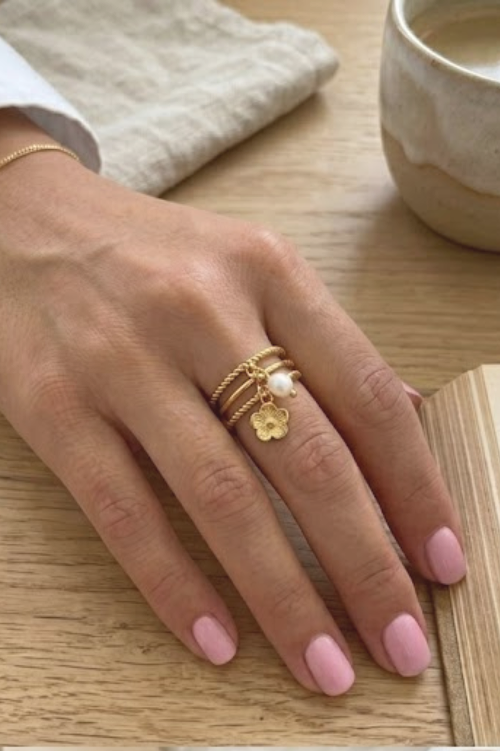 Main portant une bague ajustable dorée avec fleur et perle – bijou délicat femme acier inoxydable