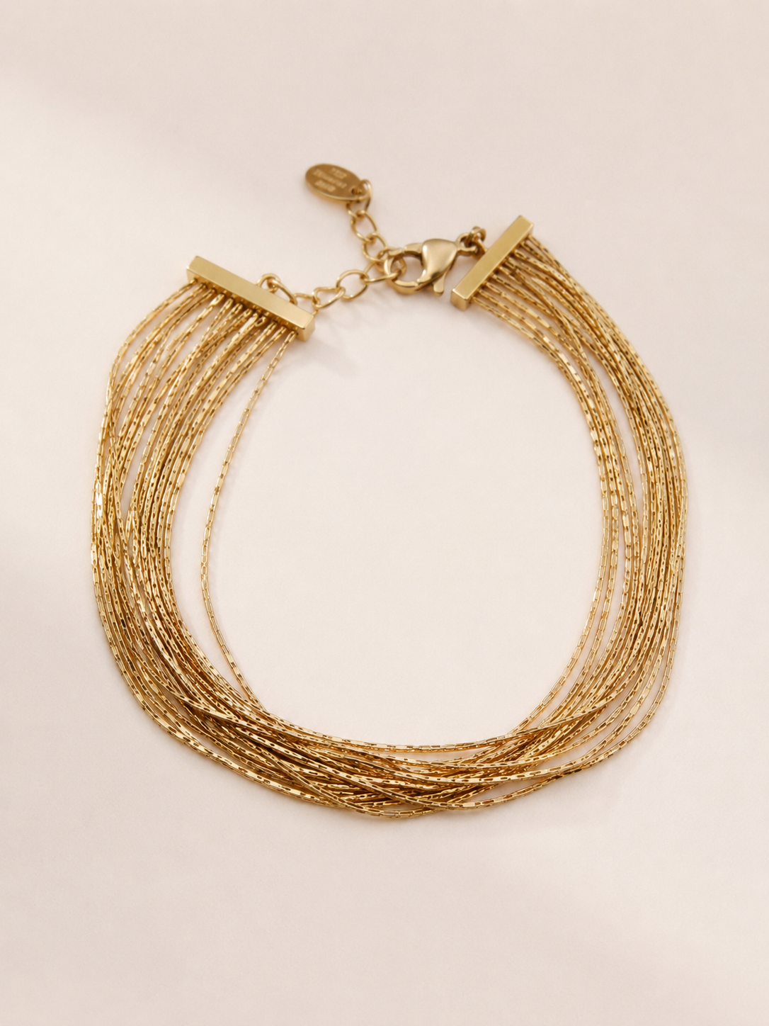 Bracelet Kali doré multi-rangs en acier inoxydable sur fond beige naturel