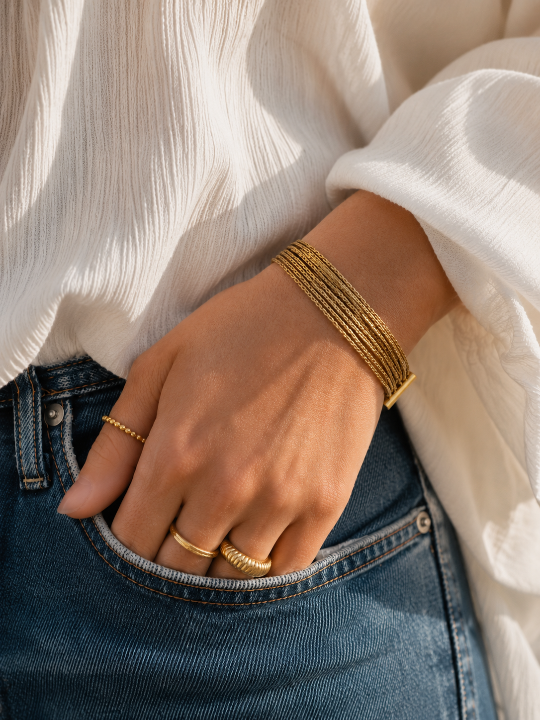 Bracelet Kali porté avec blouse blanche et bijoux dorés dans une ambiance douce et élégante